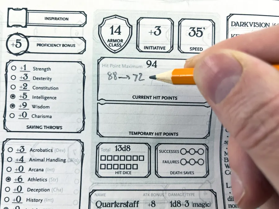 A hand filling in a character sheet with a pencil